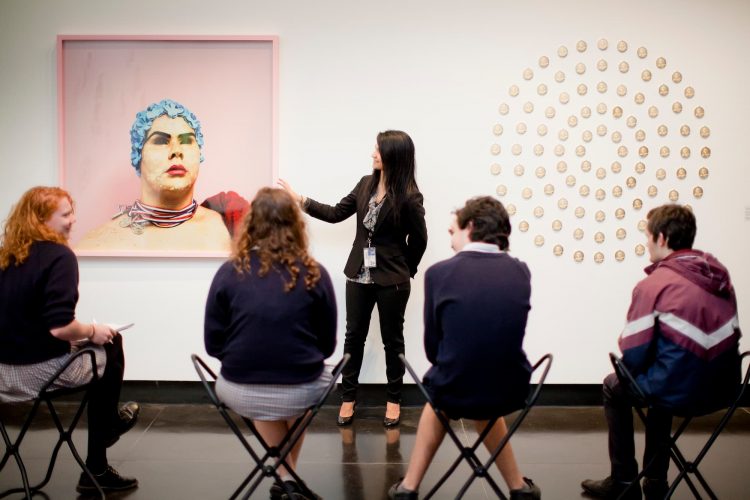 A teacher talks about artwork to sitting students